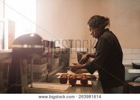 Baker Cutting Brownies At The Counter Of A Commercial Kitchen