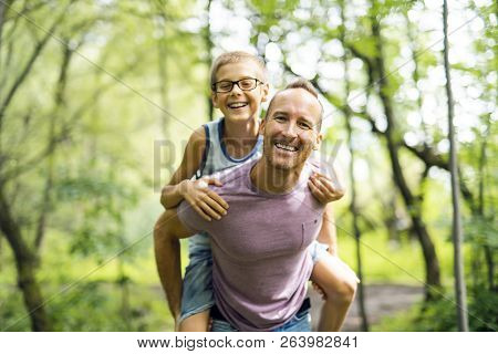Father Giving His Son A Piggyback Ride, Having Fun