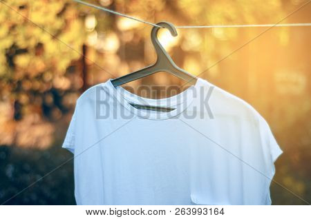 White T-shirt Hanging On A Clothespin Hanger Nature On Blur Background