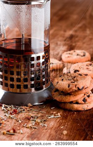 french press with hot tea and fresh baked cookies closeup on wooden table