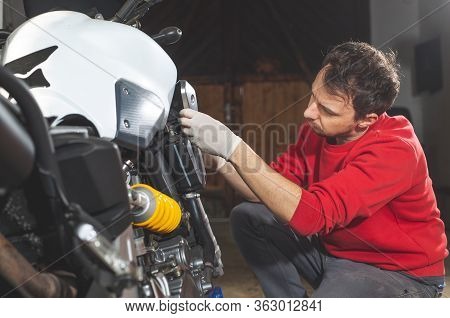 Man Repairing, Doing Maintenance Of His Motorcycle, Motorbike In The Garage, Reapir Concept