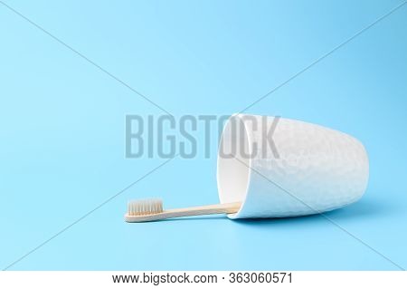 A Bamboo Toothbrush In A White Glass Lies On A Light Blue Background. Zero Waste And Without Plastic