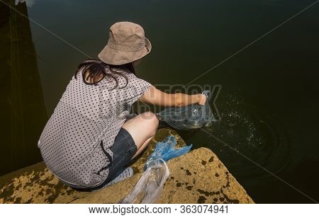 Asian Or Thai Woman At Temple Small Pier. Woman Releases Alive Fishes In Plastic Bag To River. Image