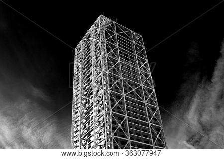 Skyscraper In Barcelona Surrounded By Clouds And Dark Sky In The Background