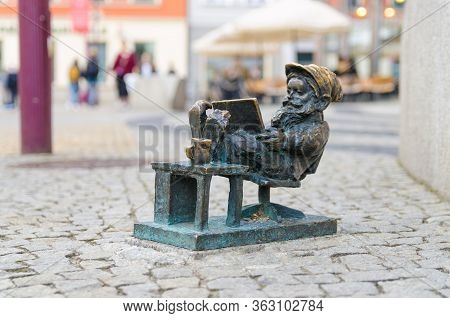 Wroclaw, Poland, May 7, 2019: Dwarf Is Sitting And Reading A Book, Famous Bronze Miniature Gnome Wit