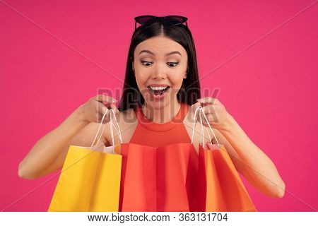 Image Of Joyous Young Asian Woman Expressing Surprise And Holding Colorful Paper Shopping Bags Isola