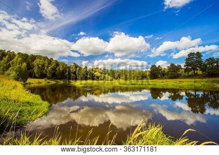 Beautiful Saturated Scenic Summer Landscape Of River Under Dramatic Blue Sky With Clouds In Brightly