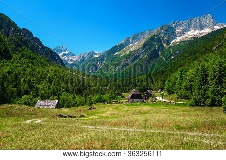 Amazing Summer Alpine Landscape With Rural Houses And High Snowy Mountains In Background, Trenta Val