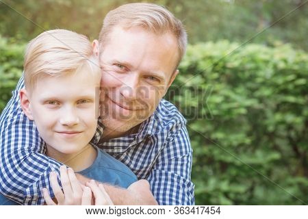 Father Hugging His Son And Smiling In The Garden. Masculinity And Fathers Day Concept.