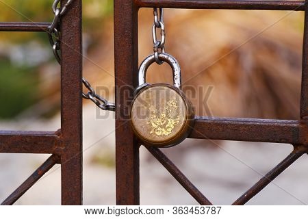 Padlock And Strong Steel Chain Wrapped Around The Metal Entrance Gate