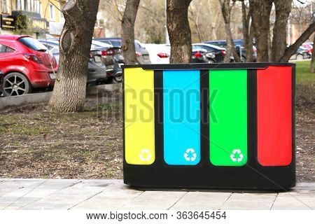 Four Waste Sorting Baskets On The City Street For Paper, Plastic, Glass And Unsorted Garbage