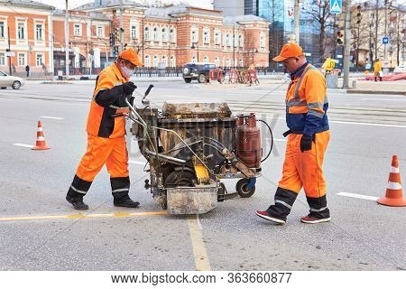 Perm, Russia - April 27, 2020: Workers Mark The Asphalt At The Bus Stop Using A Road Marking Machine