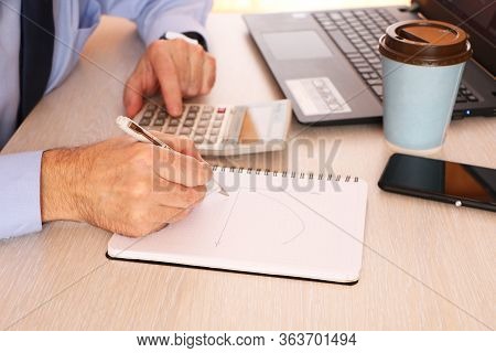 A Businessman Holds A Pen And On Schedule Calculate Data. The Graph Chart Shows The Effectiveness Of