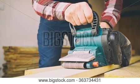 The carpenter process the wood by the belt sander