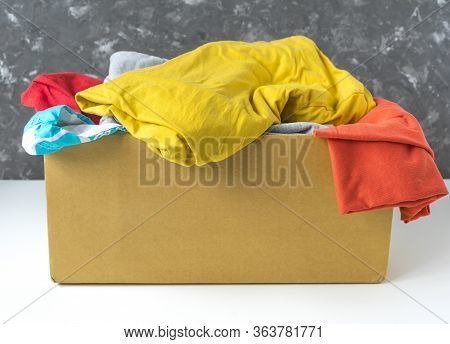 Summer Clothes In A Cardboard Box. Seasonal Clothing For Shipping Or Donation. Close Up View.