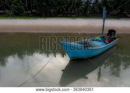 Small Blue Fishing Boat Sitting In Tidal Bay With Reflection In Water In Pythiu Thailand