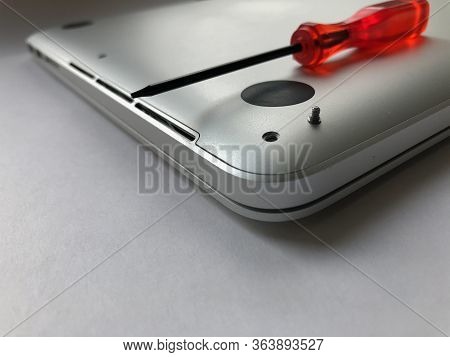 Back Side Of Silver Laptop With A Red Screwdriver. Laptop Repair Concept, Teardown.