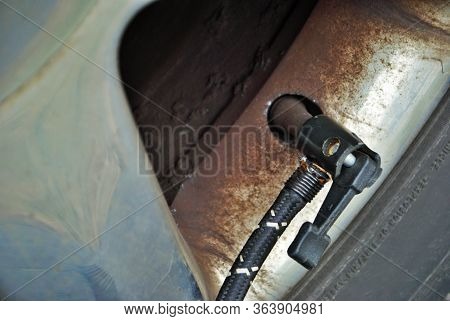 Close Up Of A Portable Air Compressor Connected To The Valve Stem Of A Car Tire