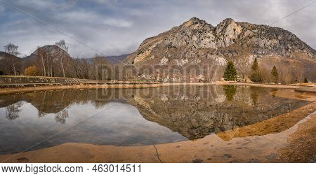 Mountain Peak And Trees Reflecting In Artificial Pond. Surba Town Hiding Behind Trees At The Foothil
