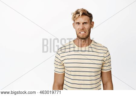 Cringe. Disgusted Blond Guy Grimacing And Clenching Teeth From Dislike, Looking With Aversion, Stand