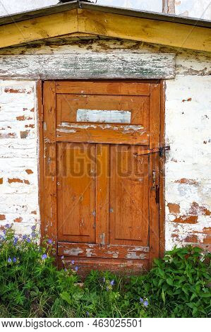 Weathered Timeworn Wooden Door Entrance To Old Brick Building.