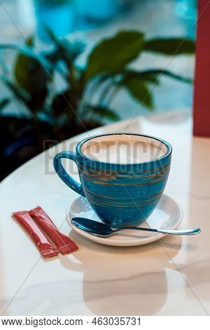 Coffee With Milk In A Blue Cup On A Wooden Table In A Cafe