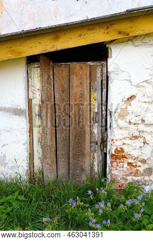 Timeworn Wooden Boarded Door Entrance To Old Brick Building.