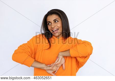 Young Hispanic Woman Smiling And Laughing. Female Model In Orange Hoodie Looking Up Cracking Fingers