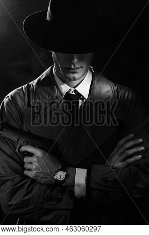 A Dark Silhouette Of A Male Detective In A Coat And Hat With A Gun In His Hands In The Noir Style. T