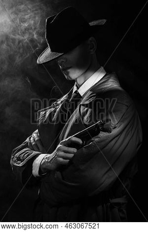 A Dark Silhouette Of A Man In A Raincoat And Hat With A Gun In His Hands In The Style Of Crime Noir.