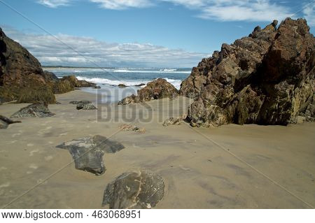 Large Jagged Rocky Outcrops Fill The Sand Covered Beach In Ogunquit Maine With Crashing Waves From T