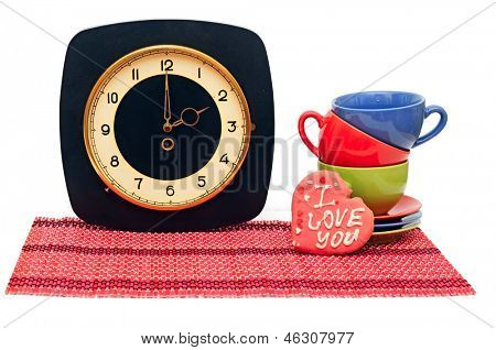 Set van kleurrijke kopjes met oude muurklok op wit. Tea time