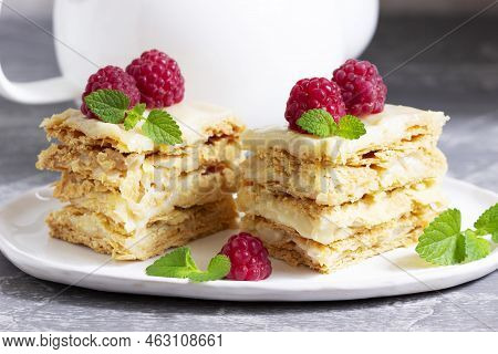 Pieces Of Napoleon Cake Decorated With Raspberries And Lemon Balm Leaves On A Light Background.