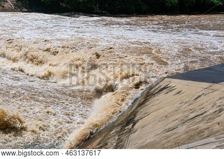 Muddy Water Streams Rushing Rapidly On A River After Rain Storm. The Rapids Passing Over A Weir, Fal