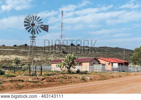 Loxton, South Africa - Sep 2, 2022: A Gravel Street Scene, With A Health Clinic, A Windmill And A Ce