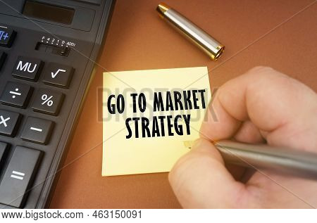 Business Concept. A Calculator Lies On A Brown Surface, A Hand With A Pen Makes An Inscription On A 