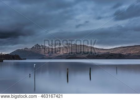 Stunning Landscape Image Of Loch Lomond And Snowcapped Mountain Range In Distance Viewed From Small 