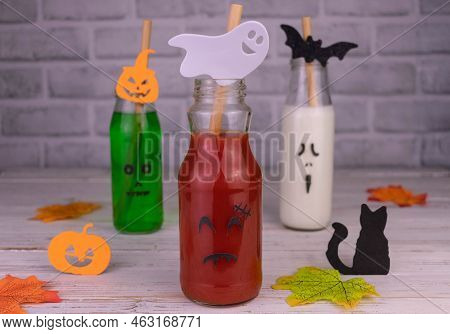 Drink Idea For Halloween Party. Drinks In Bottles With Monster Faces. Jack-o-lantern Face On Glass.