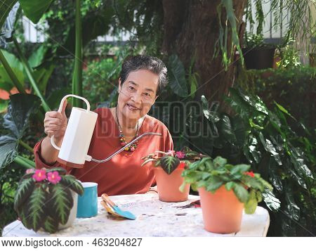 Portrait  Of Happy And Healthy Asian Senior Woman Sitting At White Table Outdoor Taking Care Of Plan