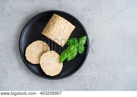 Top View Raw Tempeh Or Tempeh, Made Of Fermented Soybean Seeds. Tempeh Slices On Plate With Herbs. S