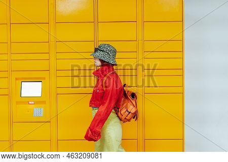 Hipster Fashion Young Woman In Bright Clothes Going Past Modern Postal Automatic Mail Terminal With 