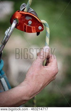 Close Up Shot Of A Man's Hands Operating A Rock Climbing Assisted Belaying Device.