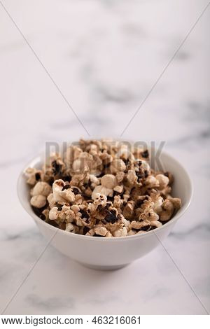 Burnt Popcorn In The Small White Bowl On Grey Ceramic