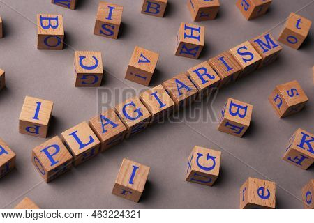 Wooden Cubes With Word Plagiarism On Grey Background