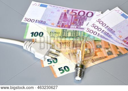 Electric Plug, Light Bulb And Euro Money Banknotes Over Grey Background. Concept For The Increase Of