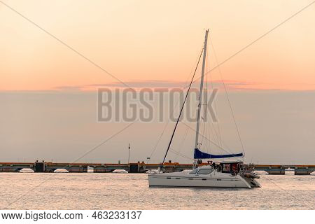 A Deserted Blurred Sailing Yacht Against A Blurred Pier And A Cloudy Sky. Lonely Boat At Sea During 