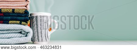 Stack Of Folded Woolen Checked Blankets And Mug In Wollen Cover, Autumn And Cold Winter Concept