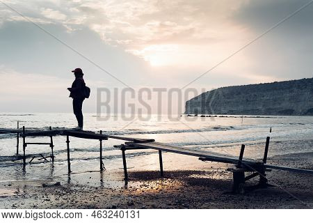 Traveller's Silhouette On An Old Wooden Pier At Zapallo Bay (apollo Bay). Episkopi, Limassol Distric