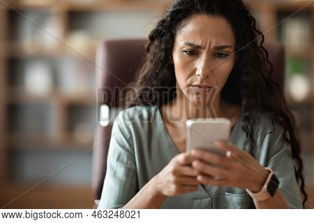Closeup Of Confused Woman Looking At Cell Phone Screen