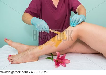 Leg Sugaring. A Beautician Makes A Sugar Paste Depilation Of A Woman's Legs In A Beauty Salon. Femal